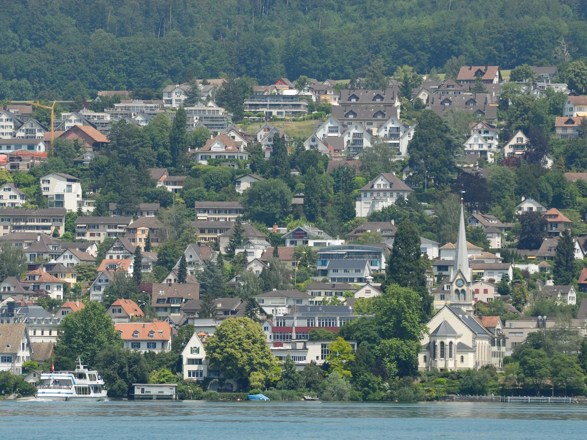 Erlenbach am rechten Ufer des Zürichsees mit reformierter Kirche, Villen am Hang und einem Kursschiff auf dem See.