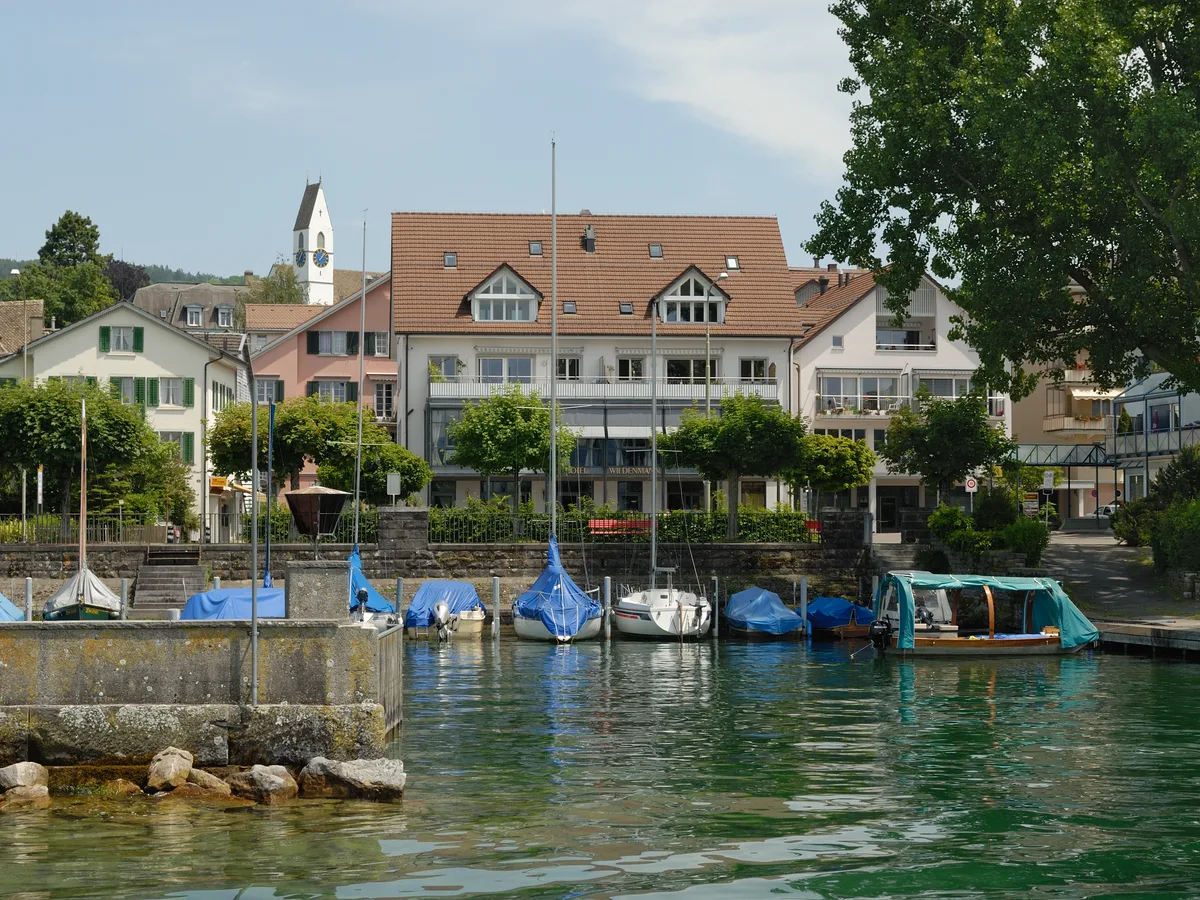 Der Seehafen von Männedorf am Zürichsee mit vertäuten Booten, der reformierten Kirche und Häusern am Ufer